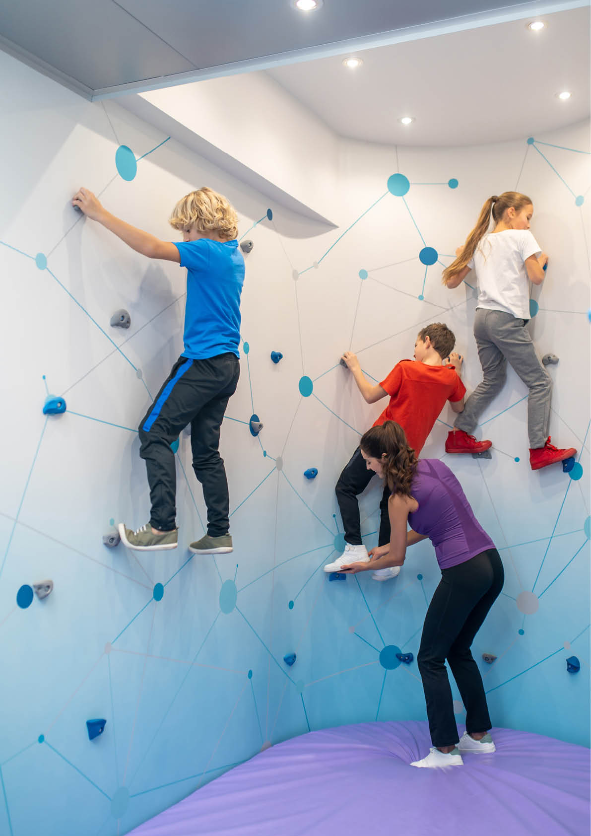 Children climbing special wall and woman helping