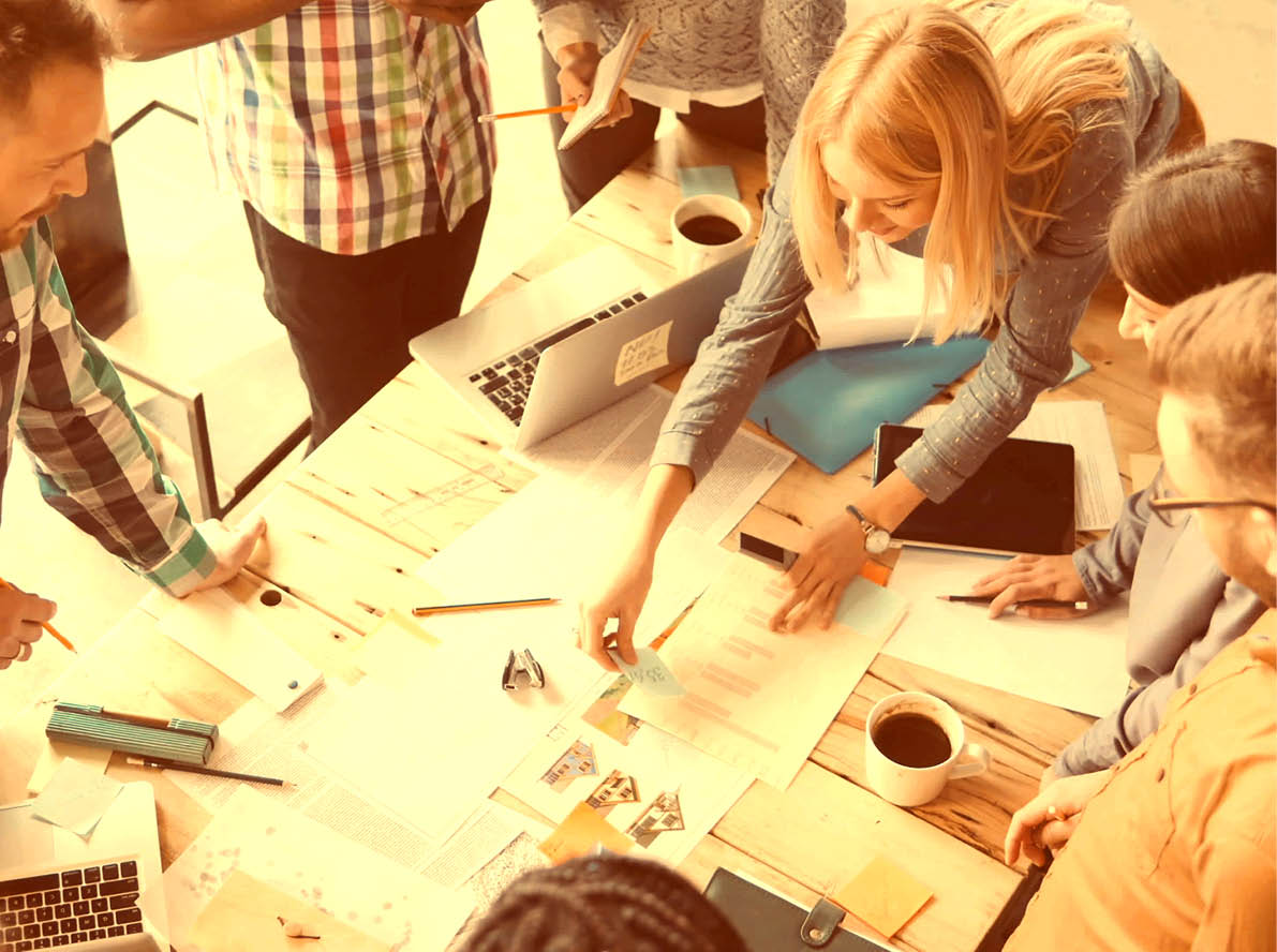 Top view of mixed race group of people standing near the table. Young business team working on start-up project together