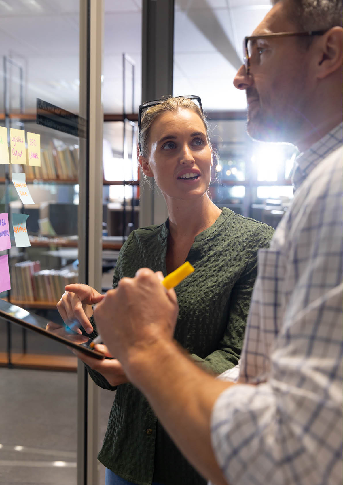 Confident caucasian professionals brainstorming while discussing over digital tablet at workplace. unaltered, creative business, technology, teamwork and modern office concept.