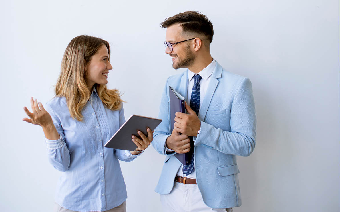 Young business people with digital tablet by the wall in the office