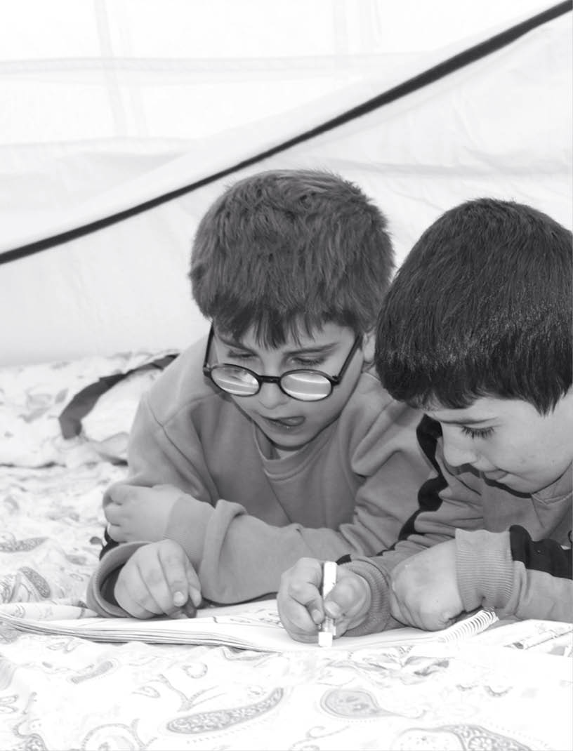 Earthquake survivor boys drawing in tent.