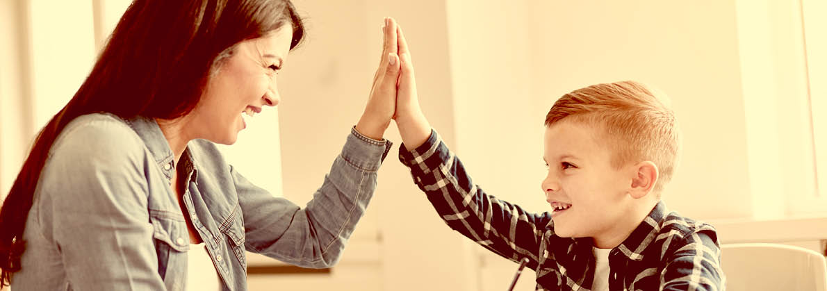 mother teaching son and helping with homework at home, son giving high five to mother