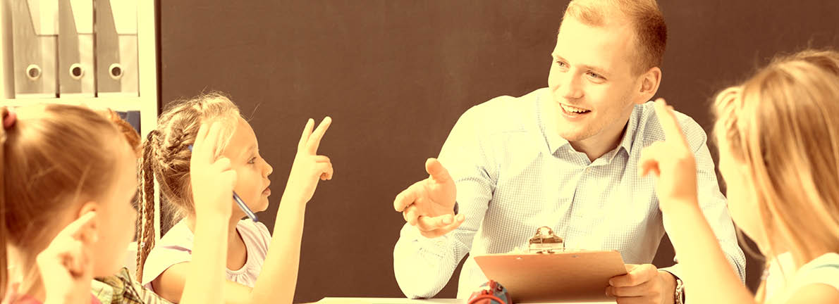 Male teacher teaching primary school children at classroom