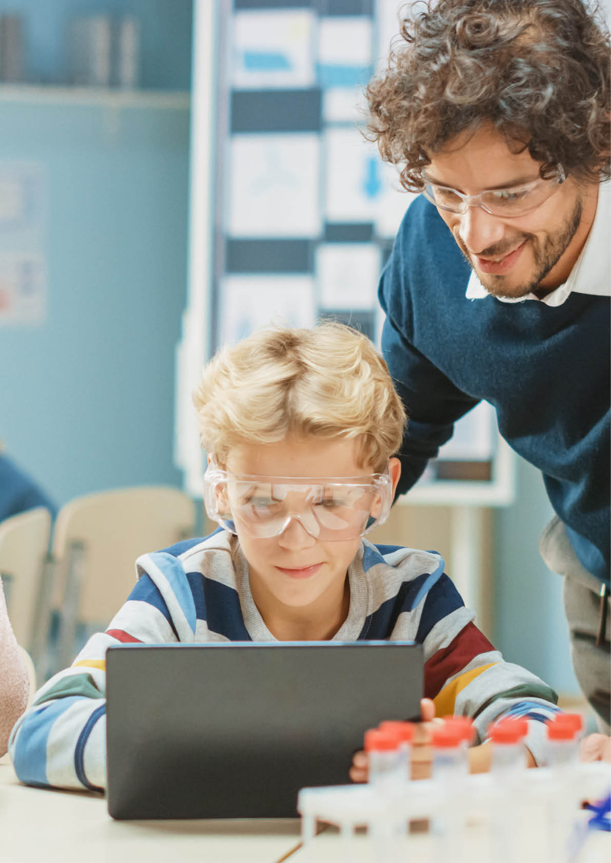 Elementary School Science Classroom: Cute Little Girl Looks Under Microscope, Boy Uses Digital Tablet Computer to Check Information on the Internet. Teacher Observes from Behind