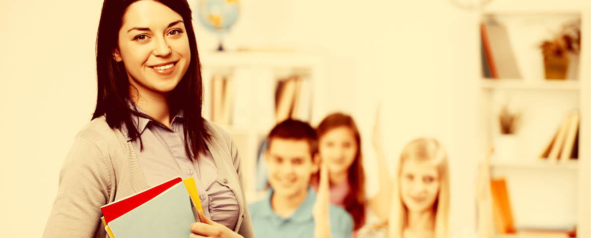 Happy teacher looking at camera with her students on background