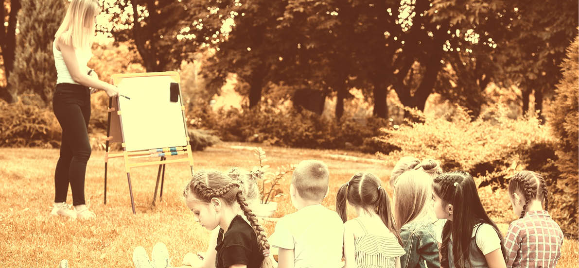 A teacher teaches a class of children in an outdoor Park. Back to school, learning during the pandemic